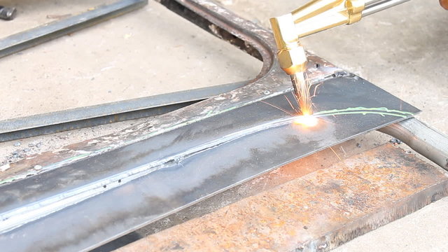 Sheet Metal Cutting With Acetylene Gas at Curve Corner. Spark splash around the ground.