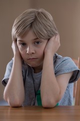 Displeased boy sitting at table