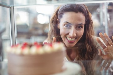 Pretty brunette looking at chocolate cake through the glass