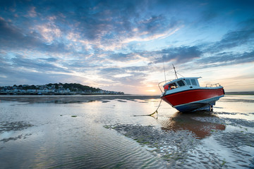Red fishing boat on the beach at Instow and looking out at Appledore across the water