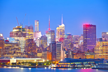 New York City skyline, modern illuminated colorful buildings in downtown Manhattan at sunset