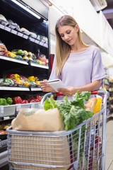 Smiling woman reading on his notepad in aisle 