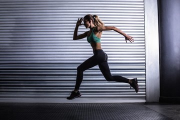 Muscular woman running in exercise room