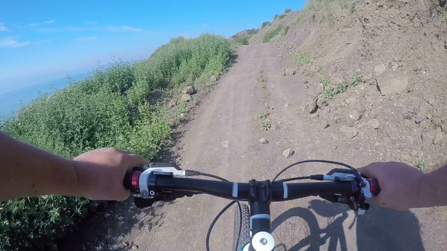 First-person POV Cyclist riding mountain bike on dirt coastal trail in Crimea