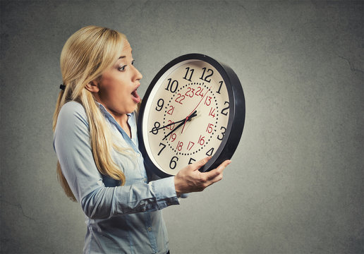 woman holding clock looking anxiously, running out of time