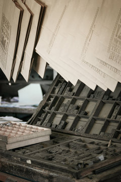 Moveable Type. A Retro Scene Of An Old Printers Shop With Typesetting Equipment On Display And Printed Documents Hanging To Dry.