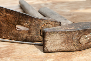 Old weathered grunge hammer and adze head closeup on plywood surface