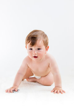 Baby boy in diapers crawling on the floor, looking in front, isolated on white background, vertical orientation.