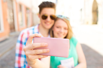 happy couple taking selfie with smartphone in city