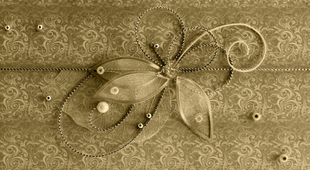 Gold horizontal handmade greeting decoration with shiny beads, embroidery, silver thread in form of flower and butterfly on background of vintage fabric