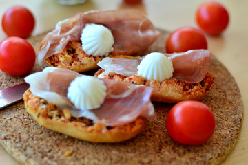 Italian Bruschetta With Mozzarella And Prosciutto On A Wooden Table