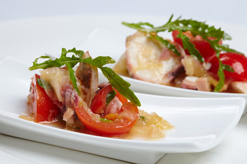 Swedish table appetizers: tomatoes, cheese, arugula, octopus, on