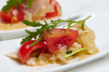 Swedish table appetizers: tomatoes, cheese, arugula, octopus, on