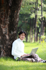 Young man using his laptop on the grass