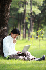 Young man using his laptop on the grass