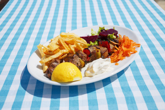 Tuna meal/Grilled tuna on plate with decorative vegetable and potato. Plaid cloth background.