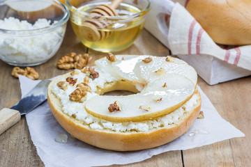 Fresh bagel with cottage cheese, pear, walnut and honey for breakfast. Concept of healthy eating.