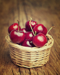 Cherries berries  in a straw basket on a wooden table