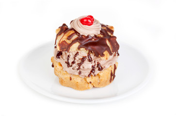 Chocolate Creampuff – A single chocolate creampuff, with whipped cream and a maraschino cherry on top. On a white plate, on a white background.