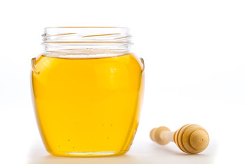 glass jar of fresh honey with drizzler isolated on white background