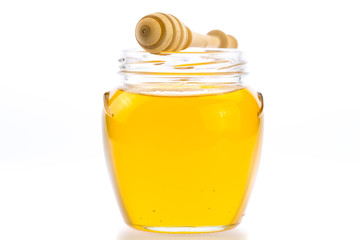 glass jar of fresh honey with drizzler isolated on white background