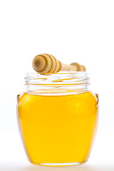 glass jar of fresh honey with drizzler isolated on white background