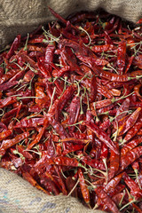 Pile of fresh red chili peppers on display in colorful red basket at market in India