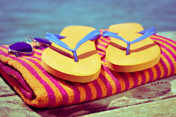 sunglasses, flip-flops and beach towel, on a wooden boardwalk