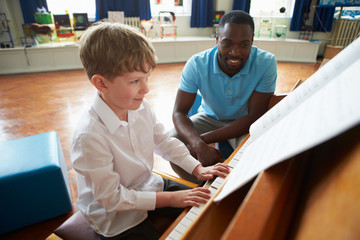 Male Student Enjoying Piano Lesson With Teacher