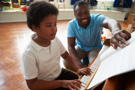 Male Student Enjoying Piano Lesson With Teacher