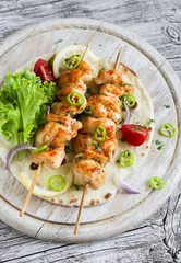 chicken kebabs and fresh vegetable salad on a homemade tortilla on a light wooden background