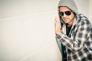 Portrait of a sad man in sunglasses sitting near the house