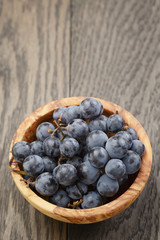 ripe isabella grapes in wood bowl on table