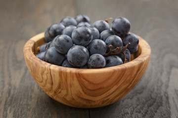 ripe isabella grapes in wood bowl on table