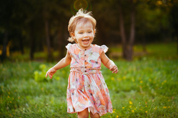 Happy cute little girl running on the grass in the park. Happine