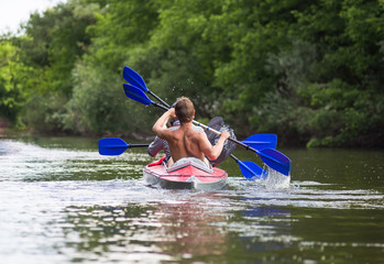Young people are kayaking on a river in beautiful nature