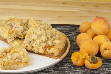 Homemade apricot cake on a plate. Freshly picked apricots on a wooden table. Homemade dessert of summer fruits.
