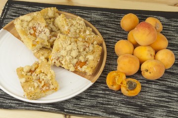 Homemade apricot cake on a plate. Freshly picked apricots on a wooden table. Homemade dessert of summer fruits.
