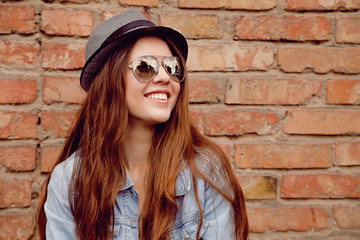 Happy beautiful woman stands near the old brick wall. 