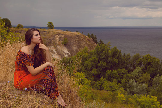 Woman sitting alone near the sea, relaxing and thinking about the meaning of life