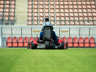  A man mowing the grass on a football stadium.