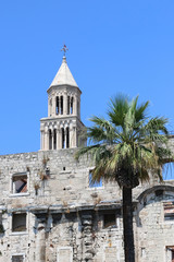 Fototapeta na wymiar Saint Domnius bell tower behind ancient wall and a palm tree. In Split, Croatia.