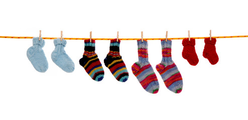 Selbst gestrickte Kinder Socken isoliert auf weiß hängend auf einer Wäscheleine mit...