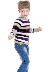 Cheerful little boy in a striped sweater and blue jeans