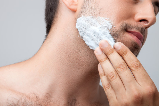 Attractive young guy is shaving his beard