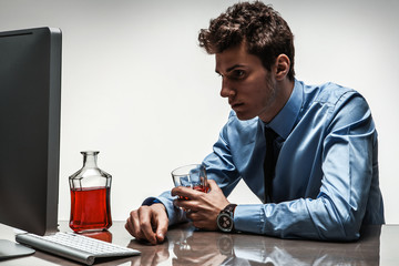 Drunk man sitting drunk at office holding glass