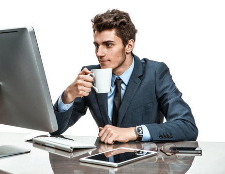 Handsome businessman having a coffee-break in office sitting at the table 