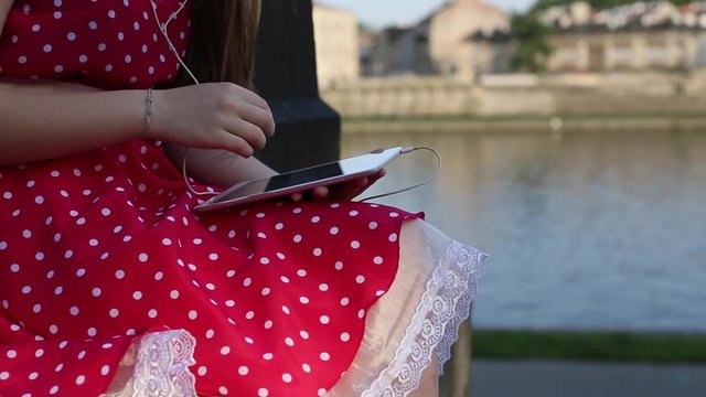 Close-up hands of young girl with the tablet on the promenade.