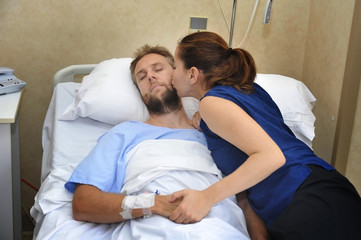 couple at hospital room man in bed and woman holding hand caring