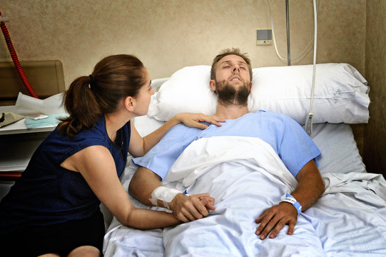 Couple At Hospital Room Man In Bed And Woman Holding Hand Caring